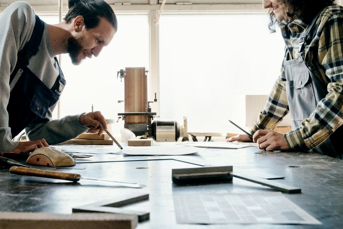 Two craftspeople working carefully at a shared workshop table.